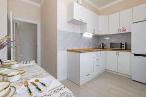 a kitchen with white cabinets and a table at Expo new life 2 in Prigorodnyy