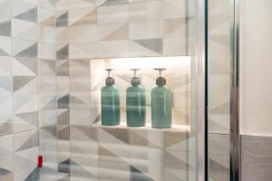 three green glass bottles sitting on a shelf in a bathroom at APARTMENT BONCIARI PERUGIA Comodo e moderno bilocale con posto auto gratuito e self check in in Perugia +73 photos