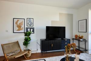 sala de estar con TV de pantalla plana en un soporte en The Tooting Escape - Glamorous 3BDR Flat with Balcony, en Londres