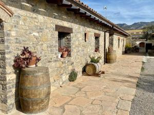 un edificio de piedra con dos barriles de madera delante de él en El Portal del Somontano ESTADILLA, en Estadilla