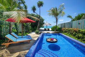 - une piscine avec une chaise, un parasol et un bol de nourriture dans l'établissement Reethi Faru, Bio Luxury Resort, à Raa Atoll