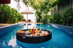 a table with food and drinks in a swimming pool at Reethi Faru, Bio Luxury Resort in Raa Atoll