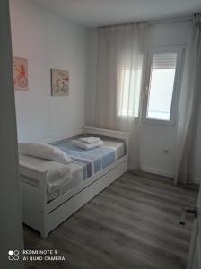 a white bedroom with a bed and a window at APARTAMENTOS LA CAPILLA in Villanueva de Arosa