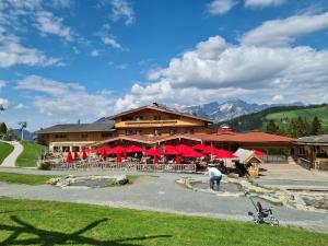 a restaurant with red umbrellas in front of a building at Alpengasthof Hochsöll in Söll