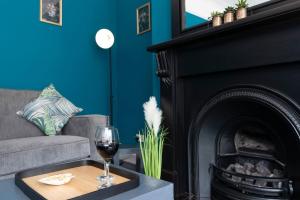 a living room with a fireplace with a glass of wine at Big House, and a lot to give! in Middlesbrough