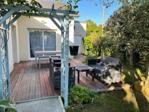 a wooden deck with a picnic table and a bench at Maison de vacances familiale in Ouistreham