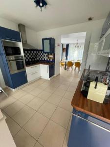 une cuisine avec des appareils bleus et blancs et une table dans l'établissement Maison de vacances familiale, à Ouistreham