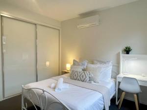 a white bedroom with a bed and a desk at Home from Home Cozy Beauty Park Front in Melbourne