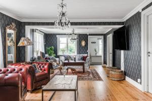 una sala de estar con muebles de cuero y una lámpara de araña. en Stubbegården - Unique swedish style en Vadstena