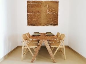 una mesa de madera y sillas en una habitación con una pintura en AL MAR Guesthouse, en São Luis