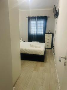 ein Schlafzimmer mit einem Bett, einer Kommode und einem Fenster in der Unterkunft Apartamento remodelado no Seixal in Seixal
