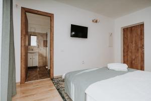 a white bedroom with a bed and a bathroom at CASA ALMI in Polovragi