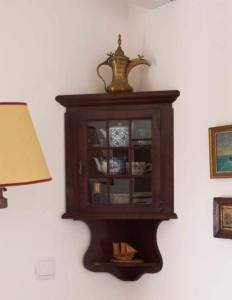 a wooden cabinet hanging on a wall with a lamp at CORALLI in Spetses