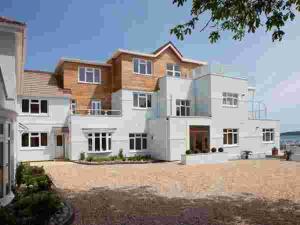 a large white house with the ocean in the background at Goodrington Lodge Holiday Apartments in Paignton