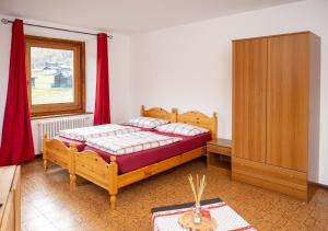 a bedroom with a bed with red curtains and a cabinet at Appartamenti Astra in Livigno