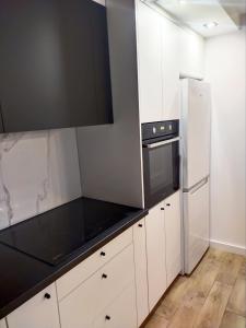 a kitchen with white cabinets and a refrigerator at Apartament 11 Listopada in Ostrołęka