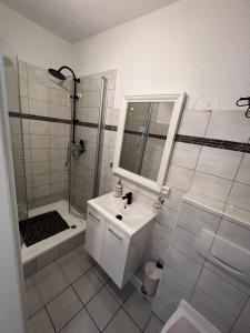 La salle de bains blanche est pourvue d'un lavabo et d'une douche. dans l'établissement Alex Apartments, à Solingen