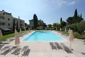 una gran piscina con sillas y sombrillas en Ginny House en Toscolano Maderno