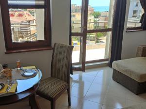 sala de estar con mesa y sillas y vistas a un edificio en Голям апартамент с прекрасна гледка кьм морето en Ravda