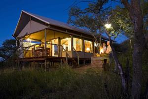 zwei Menschen stehen nachts vor einem Haus in der Unterkunft Windhoek Game Camp in Lafrenz Township