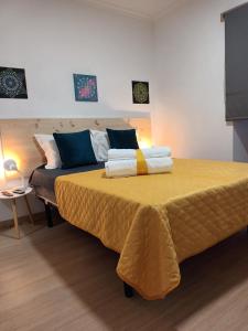 um quarto com uma grande cama amarela com toalhas em Casa Ocre Alojamento Local em Abrantes