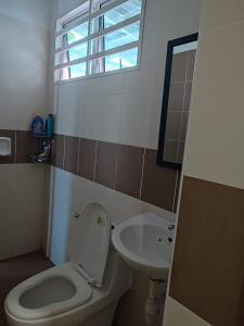bagno con servizi igienici e lavandino con finestra di Escape Homestay a Sungai Petani