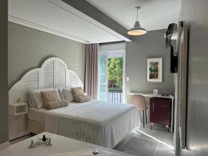 Solar Beach Hotel في فلوريانوبوليس: غرفة نوم بسرير ابيض ومكتب ونافذة