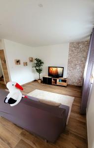 a living room with a couch and a tv at Maison La Bonbonnière chaleureuse avec parking et garage gratuit proche frontière in Forstfeld