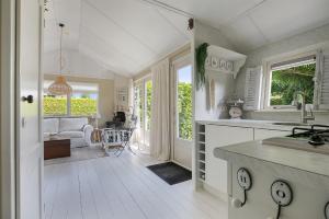 cocina con suelo y ventanas blancos y mesa en Beautiful 6-person chalet with Finnish wood-fired sauna, en Tzummarum