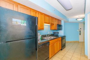 a kitchen with a stainless steel refrigerator and wooden cabinets at 1 Bedroom Suite with City and Partial Ocean Views- Bay View Resort 702 in Myrtle Beach