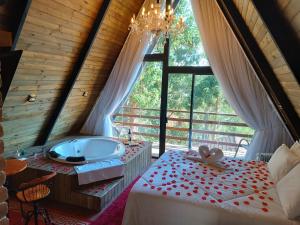 a bathroom with a tub and a bed and a window at Chalés Capivari in Campos do Jordão