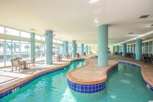 a swimming pool with tables and chairs in a building at 1 Bedroom Suite with City and Partial Ocean Views- Bay View Resort 702 in Myrtle Beach