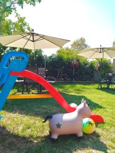 um porco de brinquedo na relva ao lado de um parque infantil em Elxis Luxury Resort em Nea Vrasna