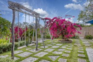 een schommel in een tuin met roze bloemen bij Bagia Bungalows in Nusa Penida