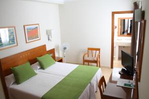 ein Hotelzimmer mit einem Bett und einem Fernseher in der Unterkunft Hotel Pujol in Las Palmas de Gran Canaria + 26 Fotos