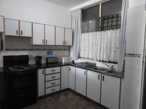 una pequeña cocina con armarios blancos y electrodomésticos negros en Marlicht Vacation Resort en Margate