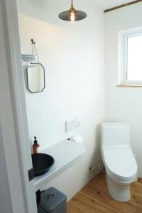 a white bathroom with a toilet and a sink at 古民家ここにわ はなれの宿 in Furano