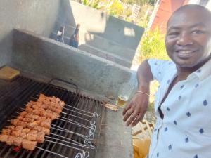 Um homem está a cozinhar comida numa grelha. em Villa CHRIS, Calme et Sérénité em Andilana