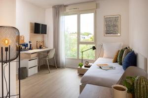 a living room with a bed and a desk and a window at Apparteo Montpellier in Montpellier