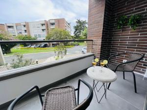 a balcony with chairs and a table with wine glasses on it at Lujoso Aparta Suite campestre en Llanogrande in Rionegro