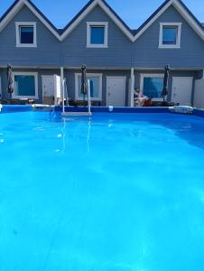 a large swimming pool in front of a house at Domki Turkusowe Zacisze in Sarbinowo
