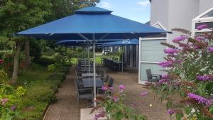 un parasol bleu avec des chaises et des tables dans un jardin dans l'établissement Hotel Restaurant La Tour Romaine - Haguenau - Strasbourg Nord, à Schweighouse-sur-Moder