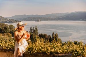 a woman in a hat standing on a hill looking at the water at Villa Antica Colonia - Lake Orta - Suite Apartments Adults Only - SPA & Wellness in Pettenasco