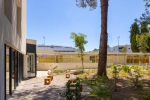 a building with a tree and benches in front of it at Apparteo Montpellier in Montpellier