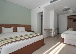 a bedroom with a large bed and a desk at Express Vieiralves in Manaus