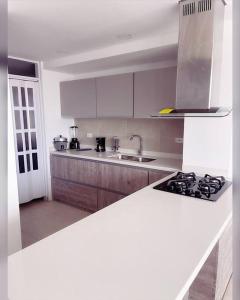 a white kitchen with a stove and a sink at Apartasuite deluxe in Popayan