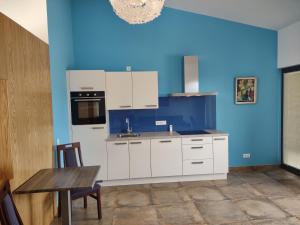 una cocina con armarios blancos y una pared azul en Suites Sunny hill, en Moncarapacho