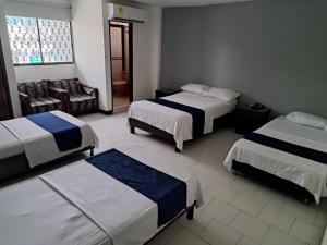 una habitación de hotel con 2 camas y una silla en Hotel Exito Barranquilla, en Barranquilla