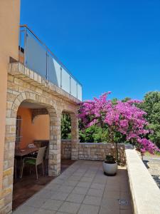 um pátio com uma mesa e uma árvore com flores cor-de-rosa em Villa Luka em Barbariga