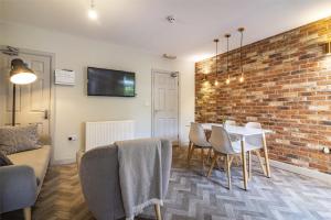 a living room with a table and a brick wall at Stay @ Baker Street Derby in Derby